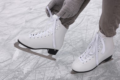 Photo of Woman lacing figure skates on ice, closeup