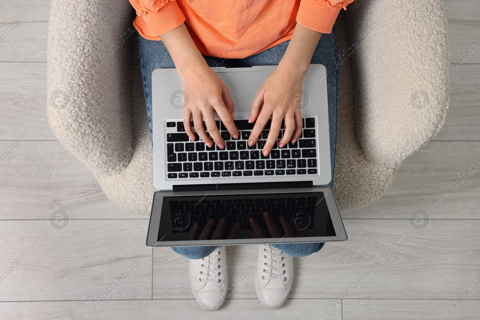 Photo of Woman working with laptop in armchair, top view