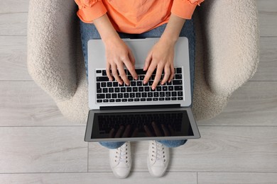 Woman working with laptop in armchair, top view