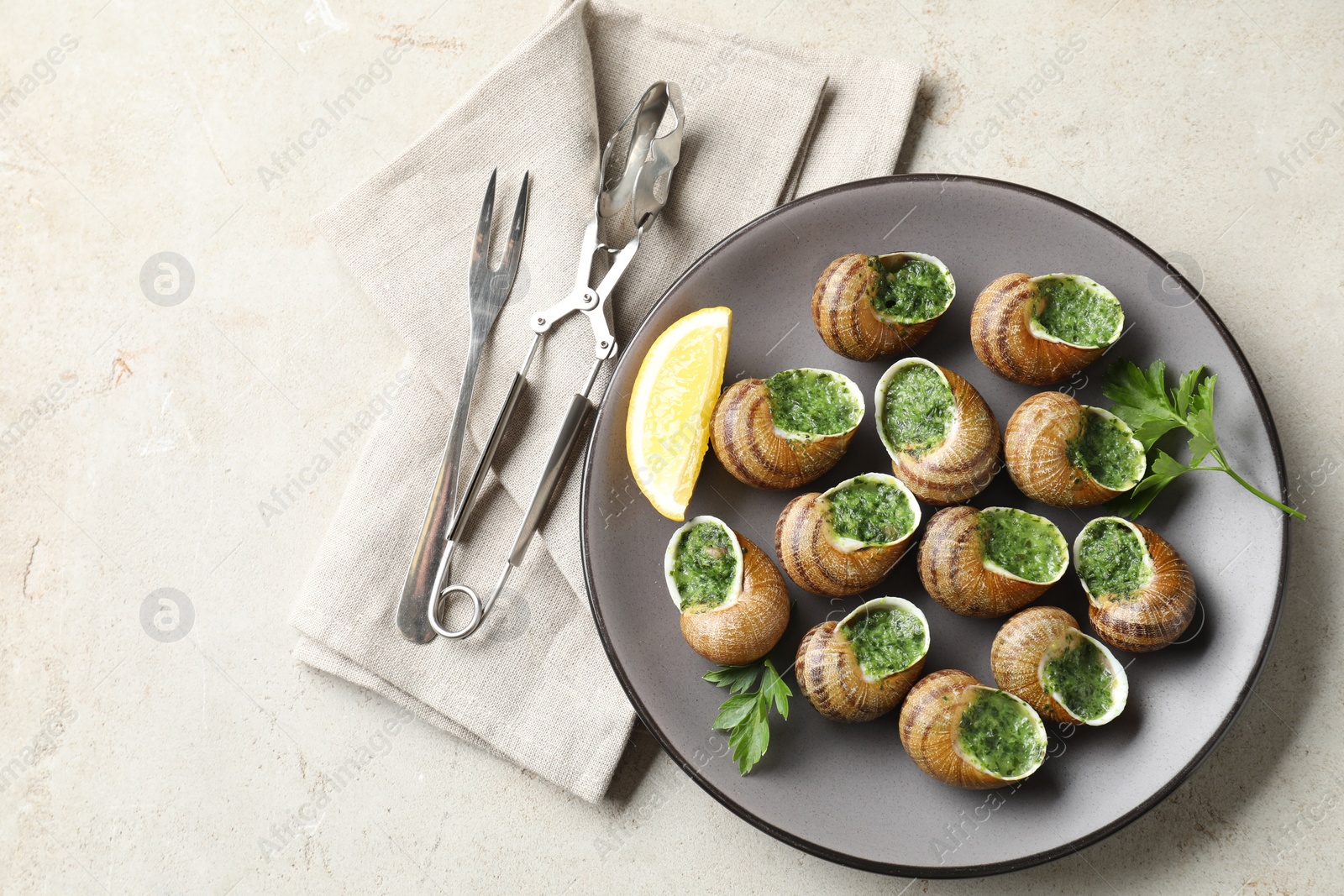 Photo of Delicious cooked snails served on light table, flat lay