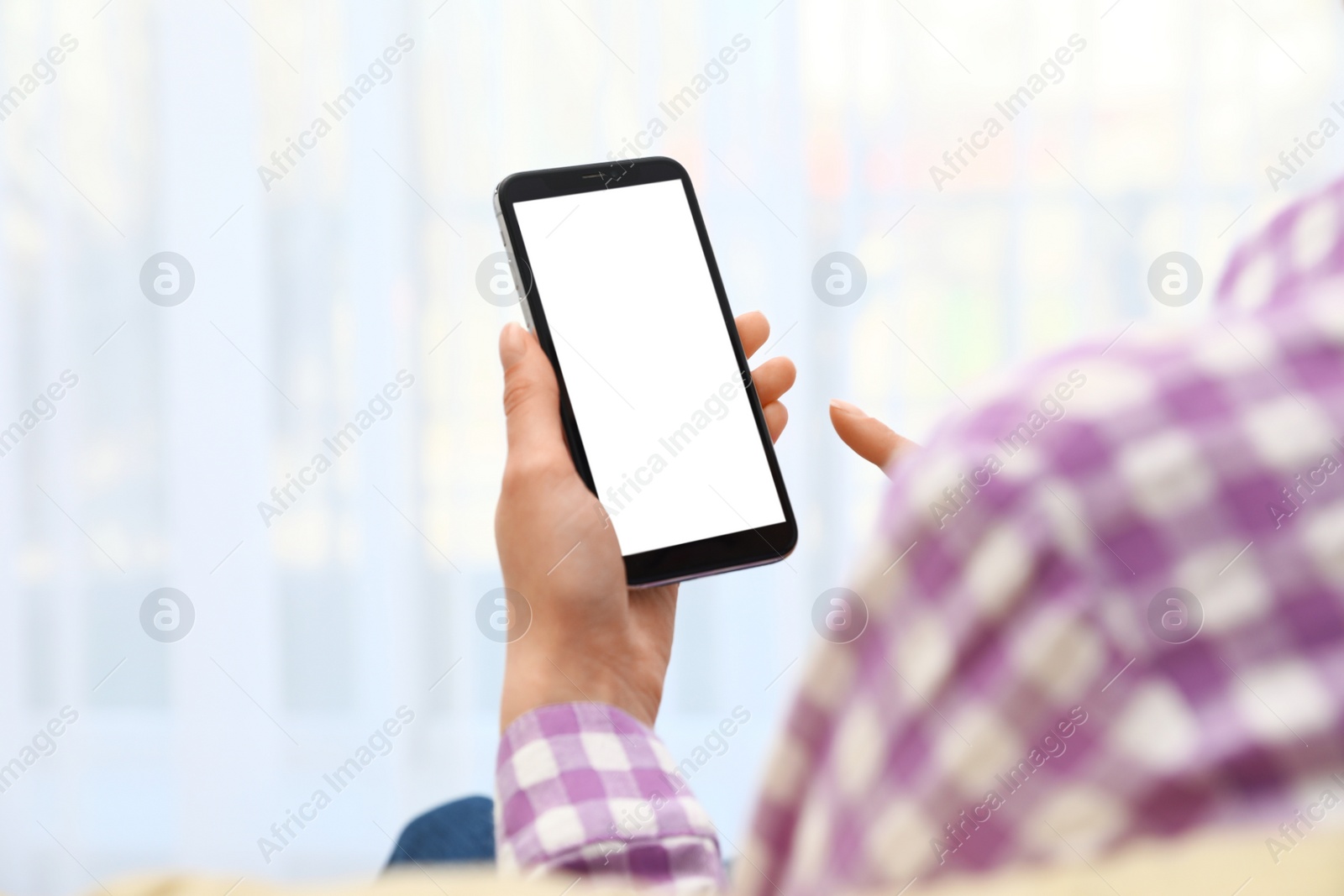 Photo of Woman holding smartphone with blank screen on blurred background, closeup of hands. Space for text