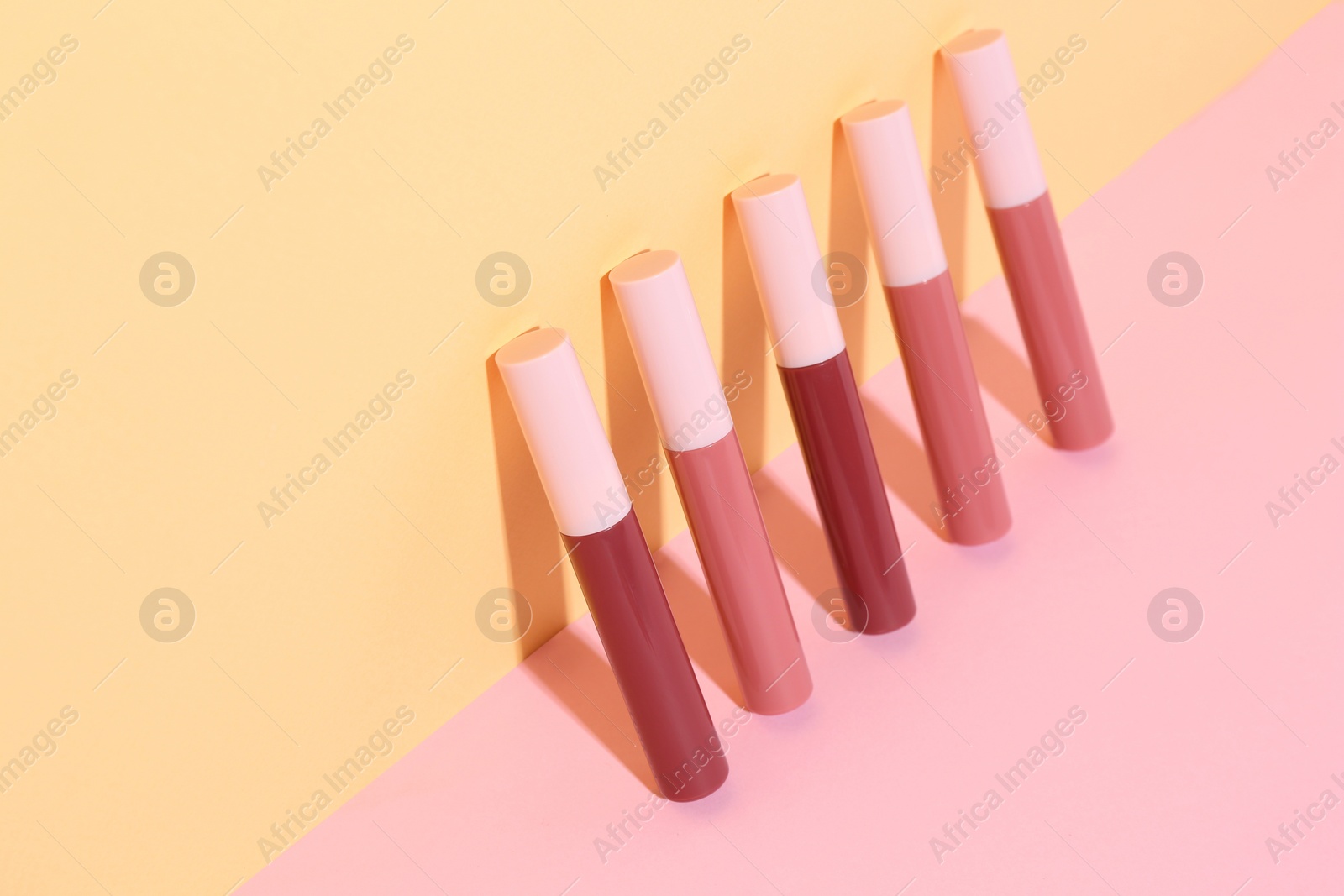 Photo of Many different lip glosses on color background