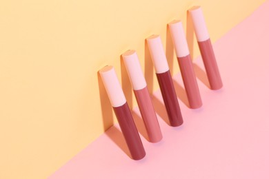 Many different lip glosses on color background