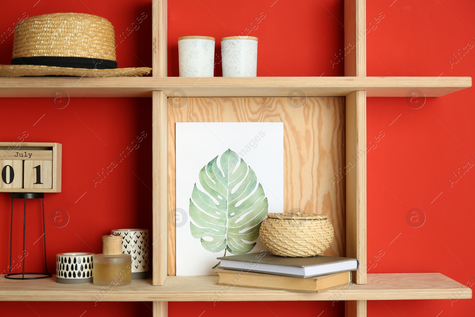 Photo of Stylish wooden shelves with decorative elements on red wall