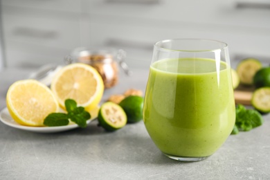 Photo of Fresh feijoa smoothie in glass on light grey table, closeup. Space for text