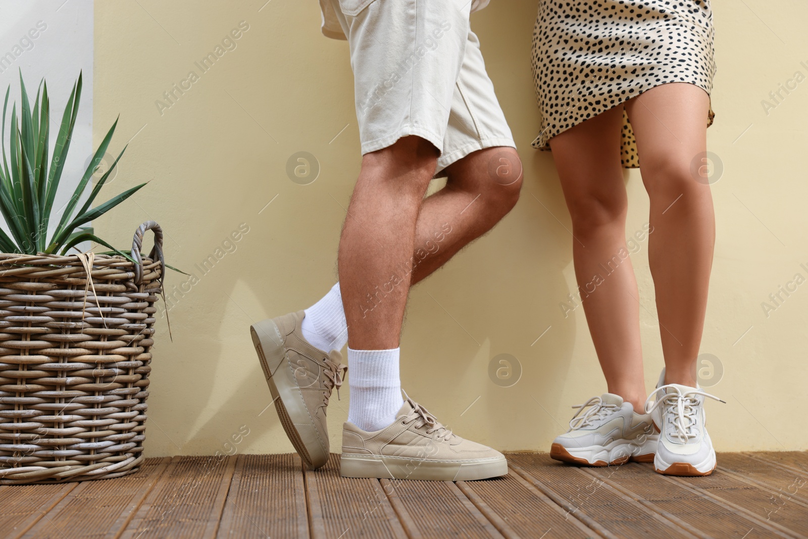 Photo of Woman and man wearing stylish sneakers near beige wall, closeup