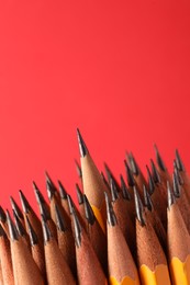 Photo of Sharp graphite pencils on red background, space for text