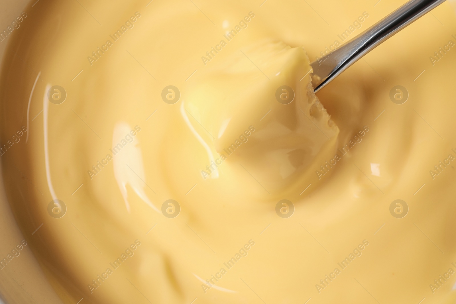 Photo of Dipping bread into tasty cheese fondue, top view