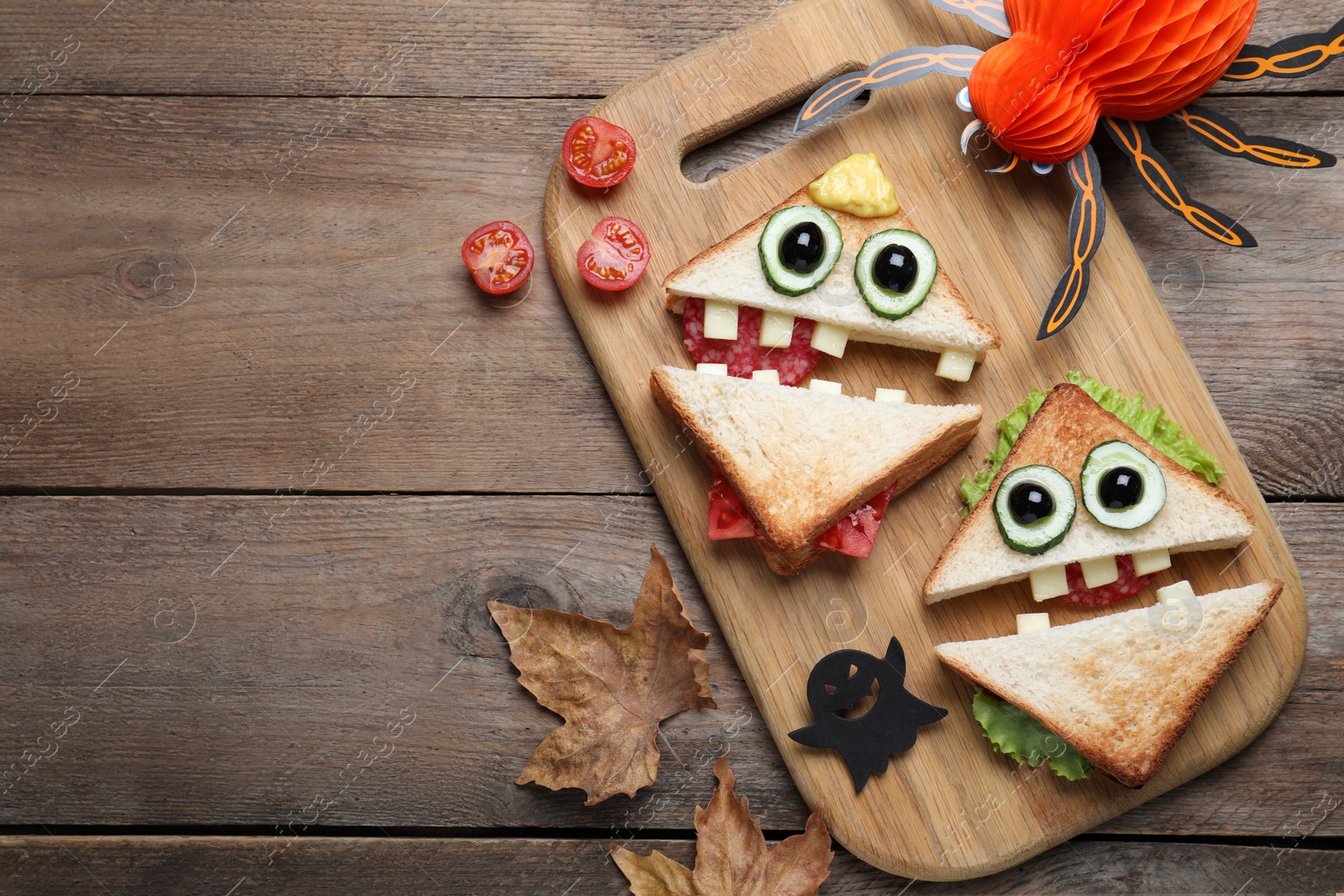 Photo of Cute monster sandwiches served on wooden table, flat lay with space for text. Halloween party food