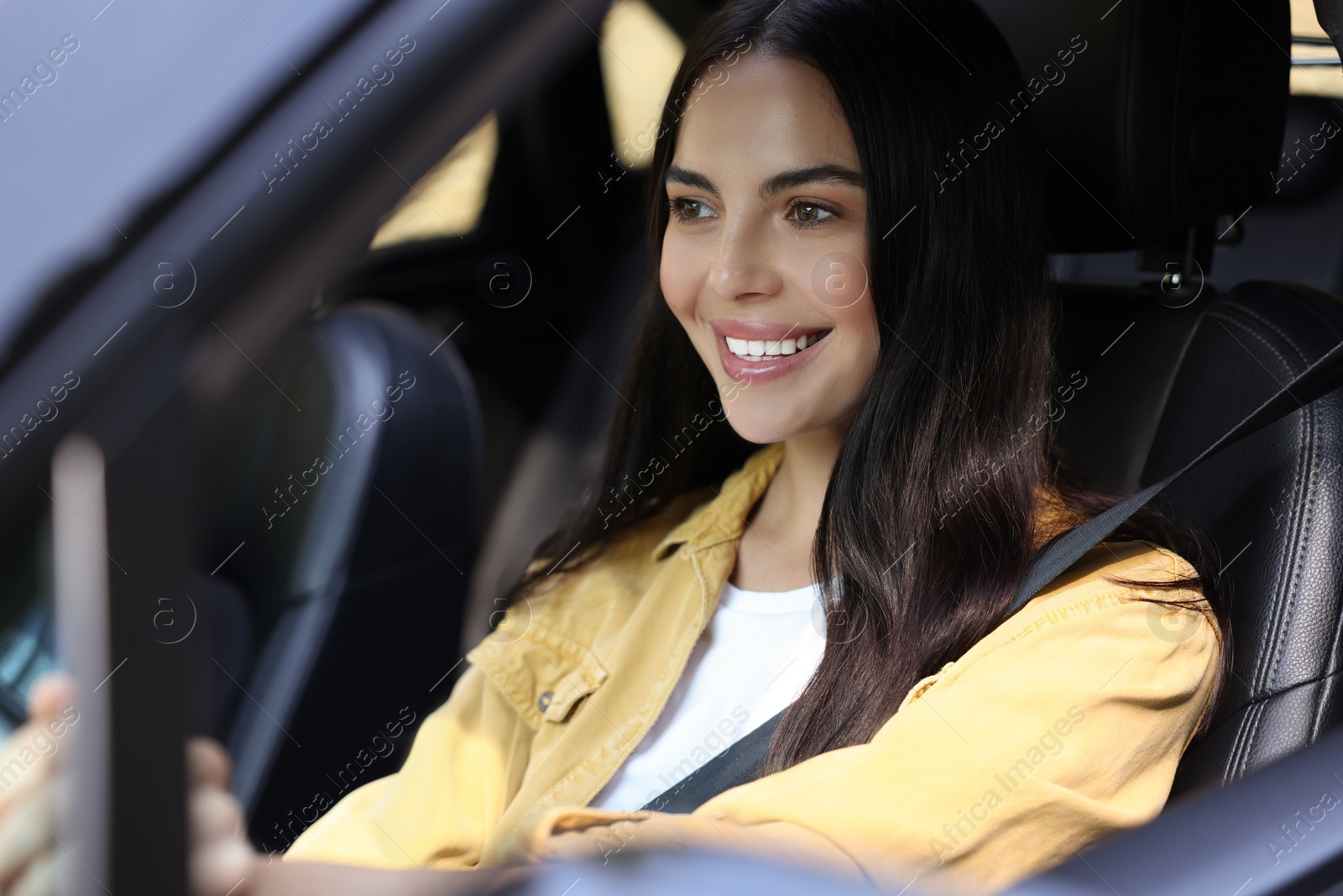 Photo of Enjoying trip. Happy young woman driving her car, view from outside