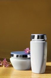 Photo of Hair care cosmetic products and beautiful flowers on wooden table
