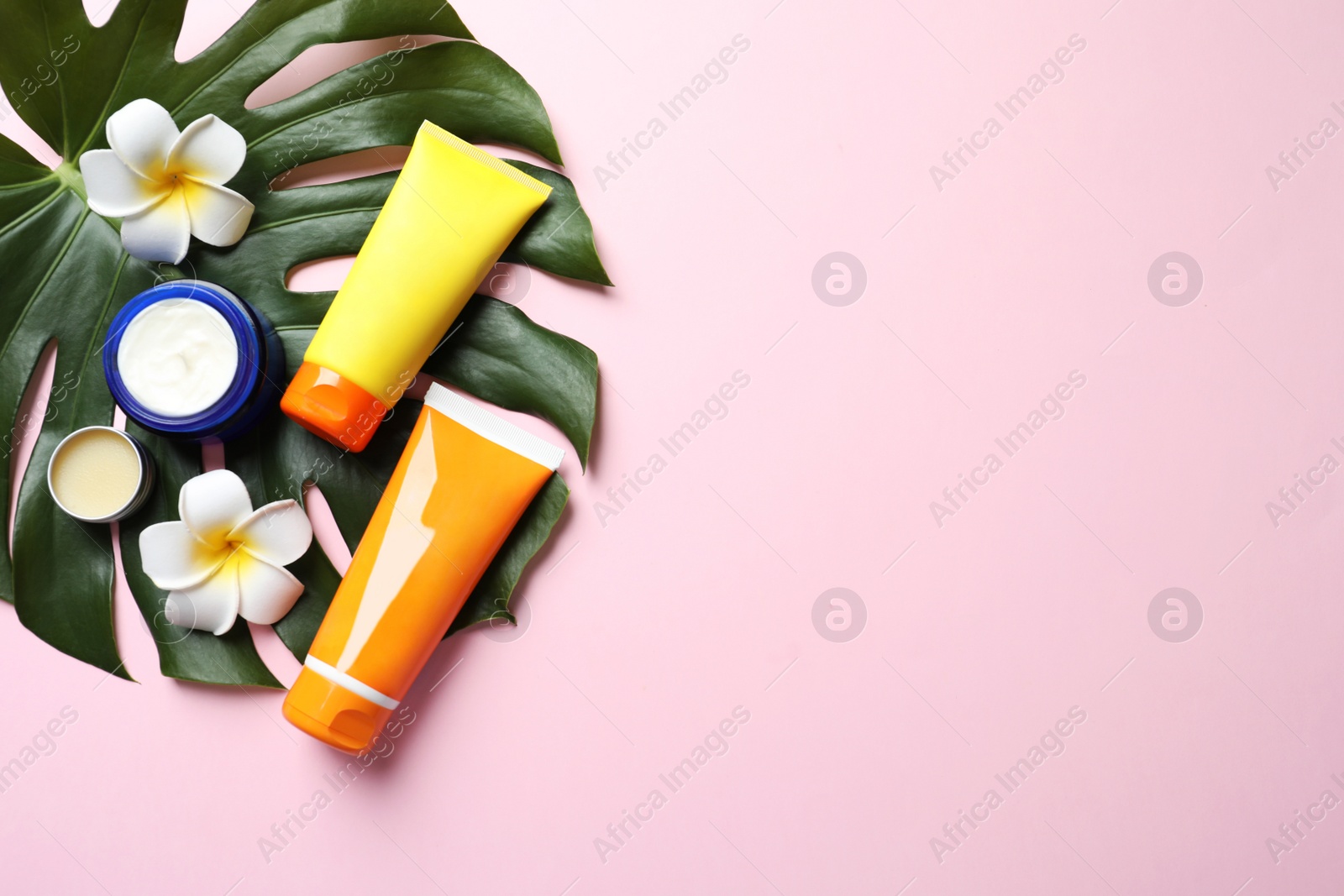 Photo of Flat lay composition with sun protection cosmetic products on pink background, space for text