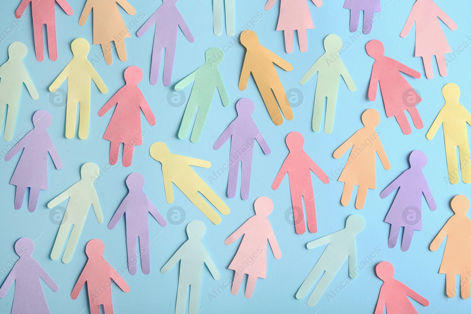 Photo of Many different paper human figures on light blue background, flat lay. Diversity and inclusion concept