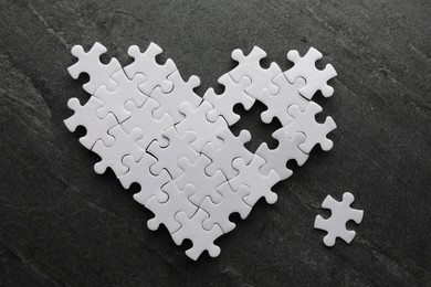 Photo of Heart made of puzzles with missing piece on black table