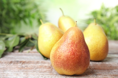 Photo of Ripe juicy pears on brown wooden table against blurred background. Space for text