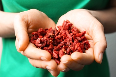 Photo of Woman holding red dried goji berries, closeup