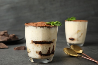 Photo of Delicious tiramisu cake in glass on table