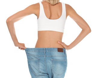 Photo of Young slim woman in old big jeans showing her diet results on white background