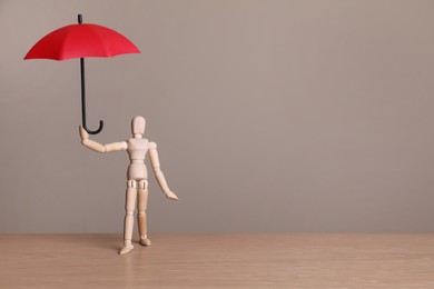Photo of Mannequin holding small umbrella on wooden table. Space for text