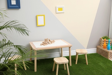 Photo of Stylish playroom interior with table, stools and green carpet