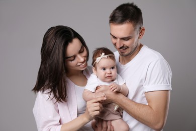 Happy family. Couple with their cute baby on grey background