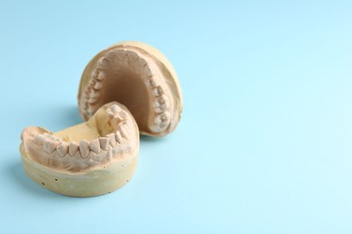 Photo of Dental model with gums on light blue background, space for text. Cast of teeth