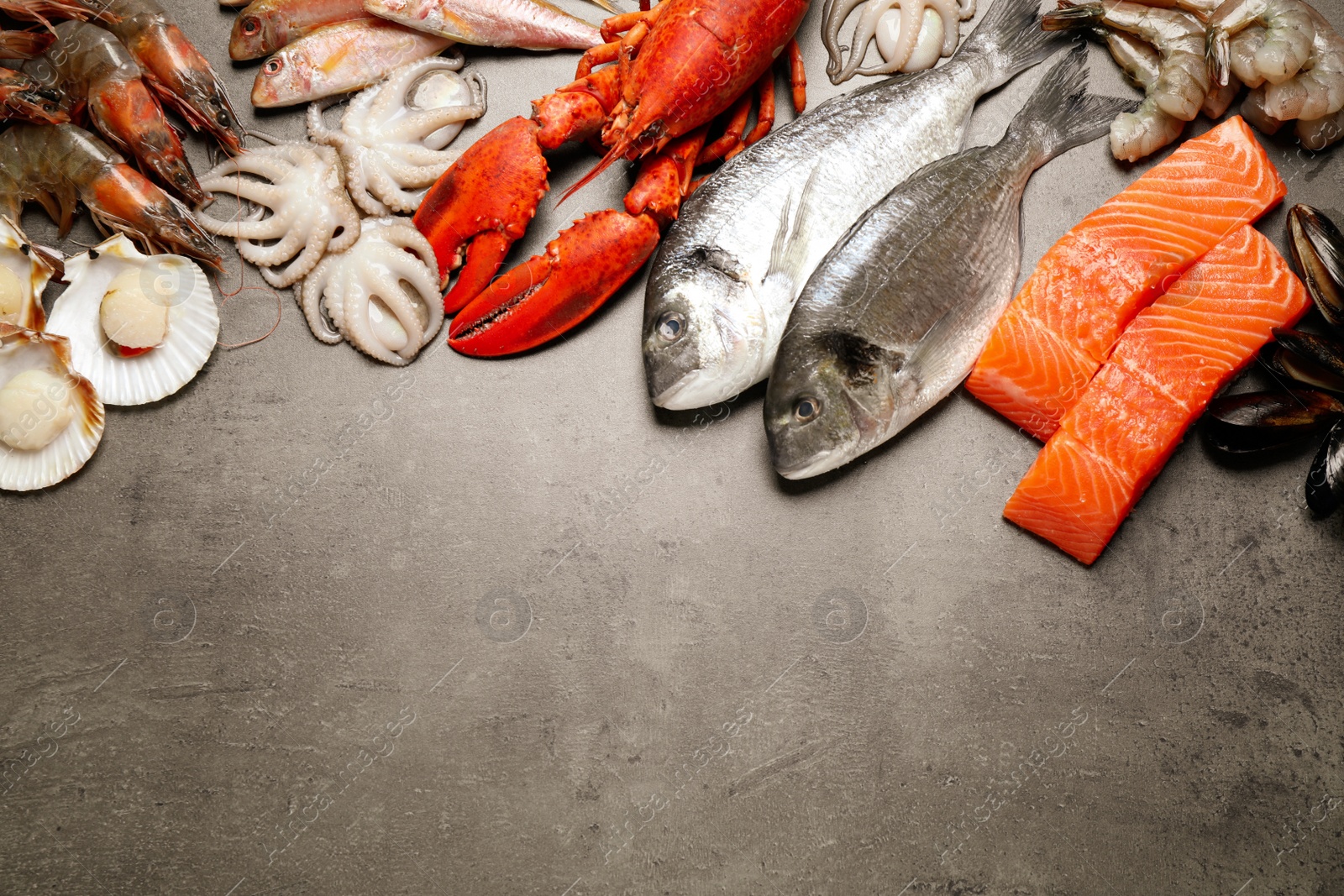 Photo of Fresh fish and seafood on grey table, flat lay. Space for text