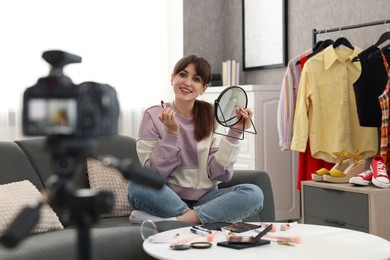 Photo of Smiling beauty blogger recording makeup tutorial at home