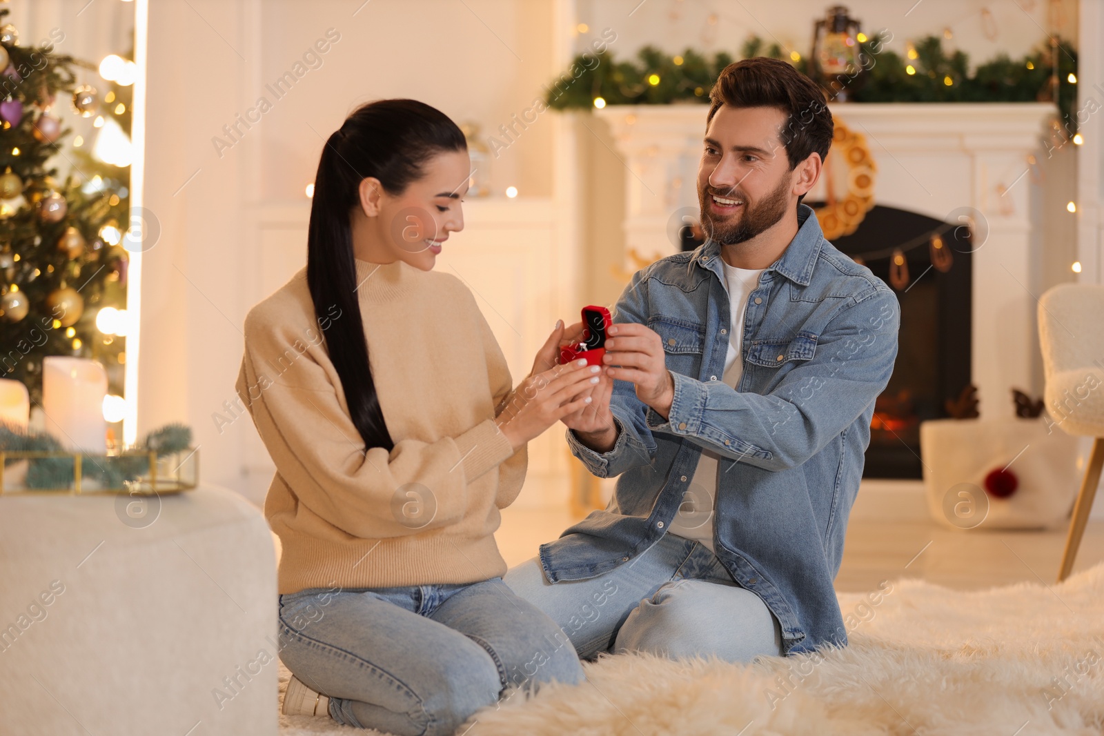 Photo of Man with engagement ring making proposal to his girlfriend at home on Christmas