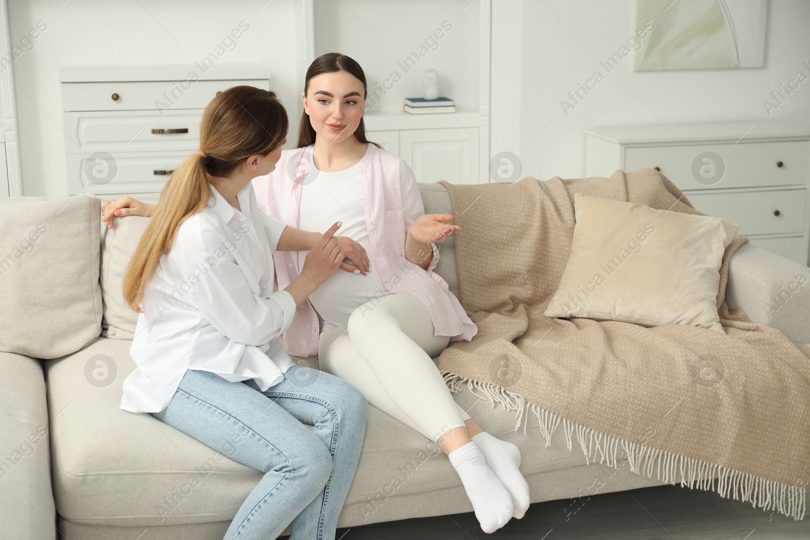 Photo of Doula taking care of pregnant woman on sofa at home. Preparation for child birth