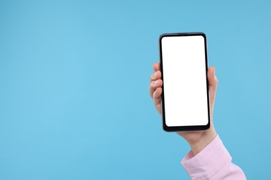 Woman holding smartphone with blank screen on light background, closeup. Mockup for design