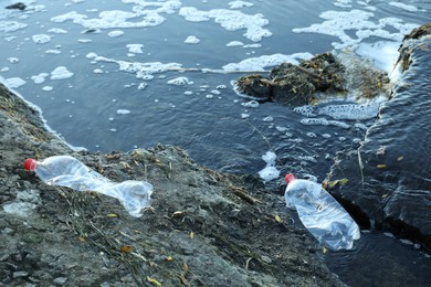 Photo of Used plastic bottles near water outdoors. Environment pollution