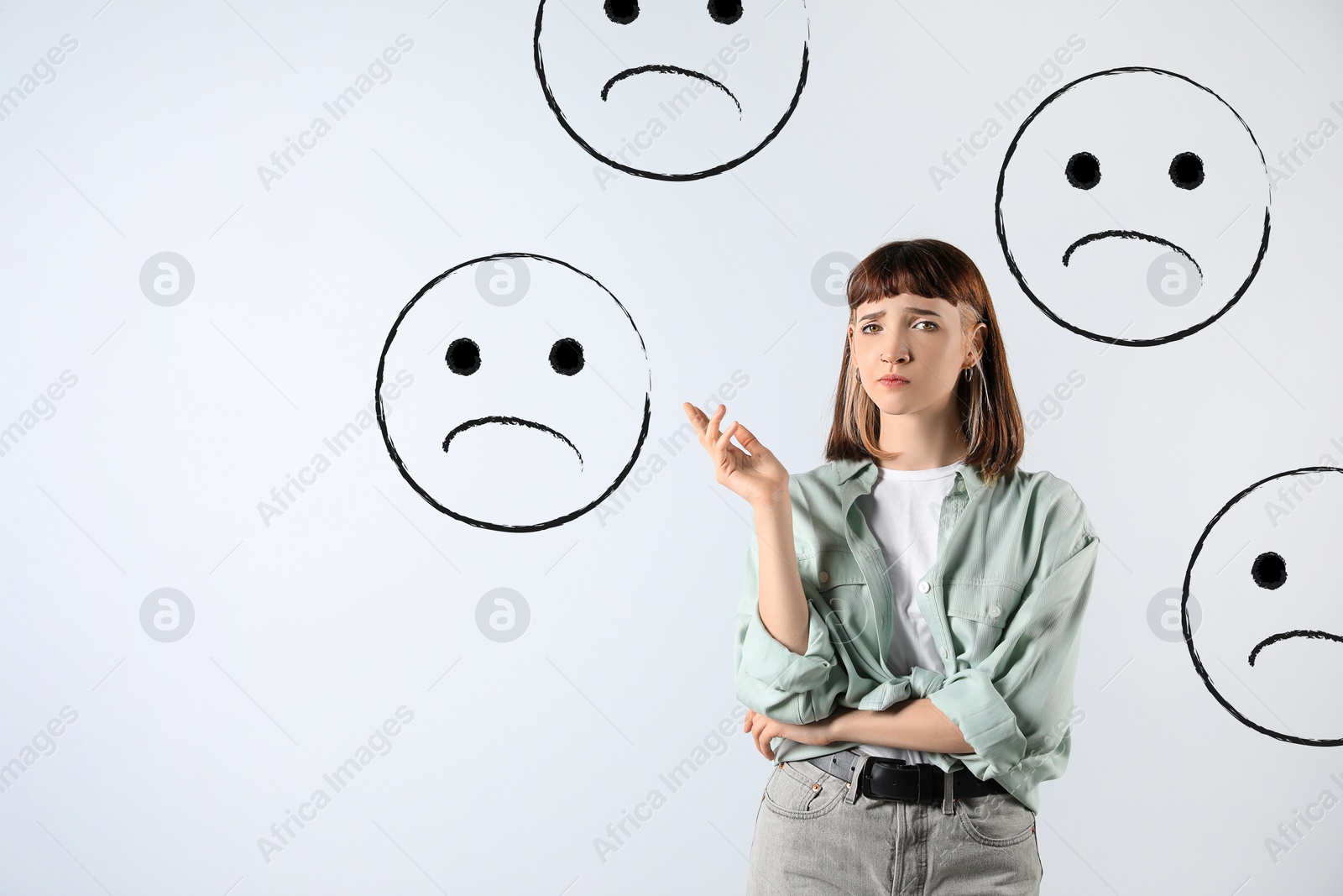 Image of Complaint. Dissatisfied girl surrounded by illustrations of sad face on light background, space for text