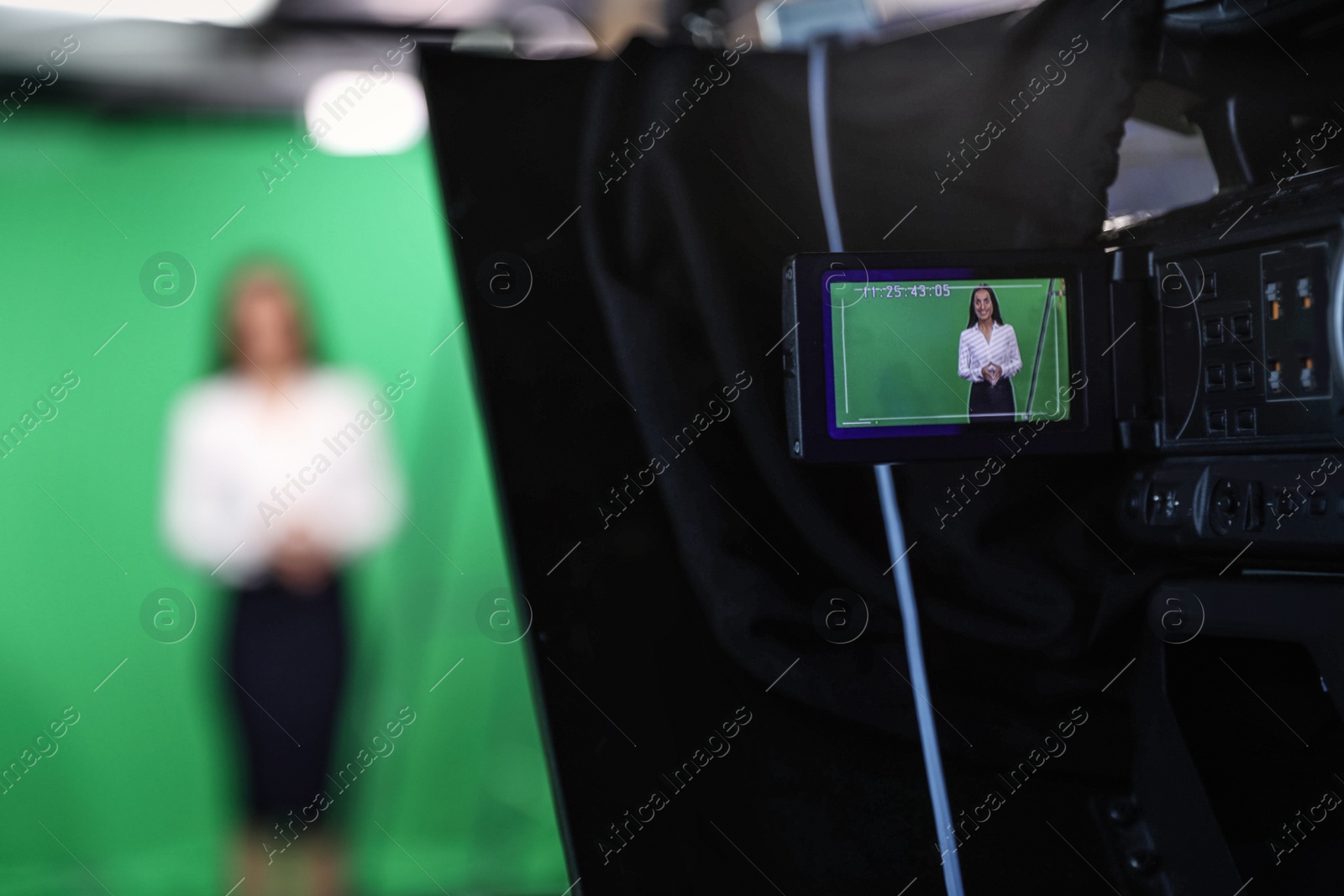 Photo of Presenter working in studio, focus on video camera screen