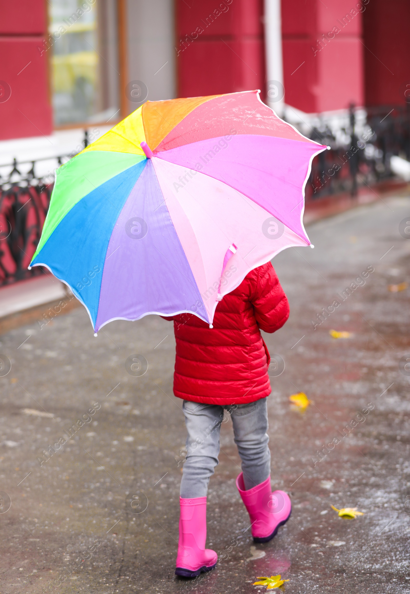 Photo of Little girl with umbrella taking autumn walk in city on rainy day