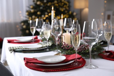 Photo of Christmas table setting with festive decor and dishware indoors