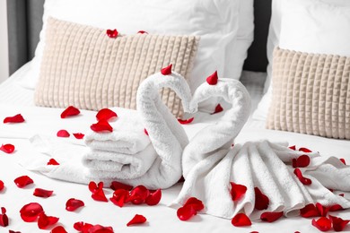 Photo of Honeymoon. Swans made with towels and beautiful rose petals on bed