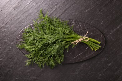 Photo of Bunch of fresh dill on dark textured table, top view