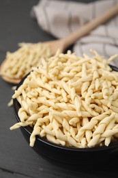 Photo of Uncooked trofie pasta in bowl on grey table, closeup