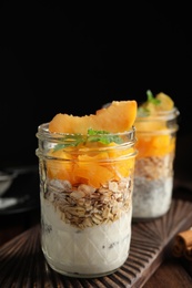 Photo of Tasty peach dessert with yogurt, chia seeds and granola on wooden table