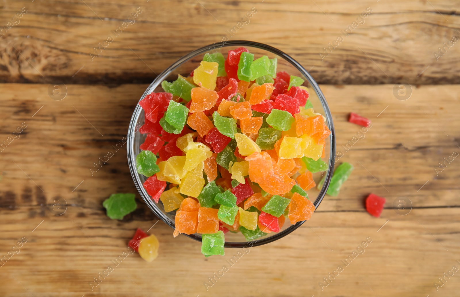 Photo of Mix of delicious candied fruits in bowl on wooden table, top view