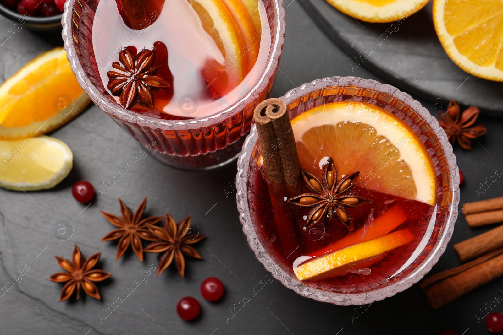 Photo of Aromatic punch drink and ingredients on black table, flat lay