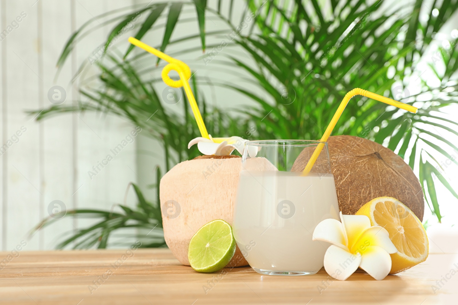 Photo of Composition with glass of coconut water on wooden table against blurred background