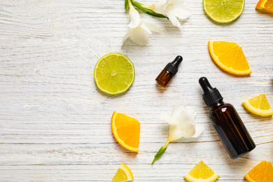 Photo of Flat lay composition with bottles of citrus essential oil on white wooden background. Space for text