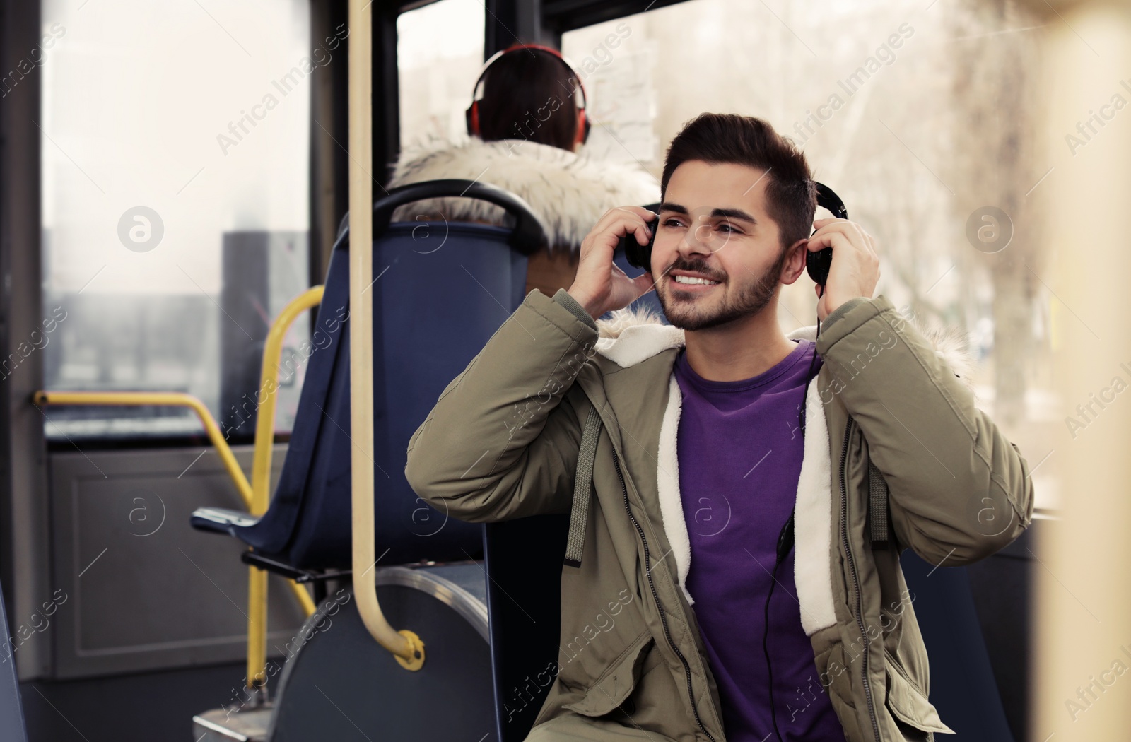 Photo of Young man listening to music with headphones in public transport