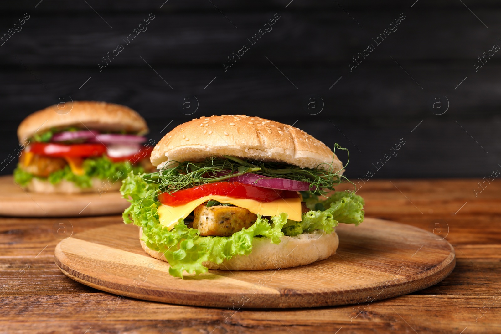 Photo of Delicious burgers with tofu and fresh vegetables on wooden table