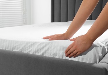 Woman touching soft mattress indoors, closeup view
