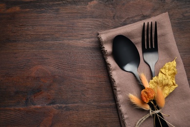 Photo of Seasonal table setting on wooden background, space for text. Cutlery with autumn decorations, top view