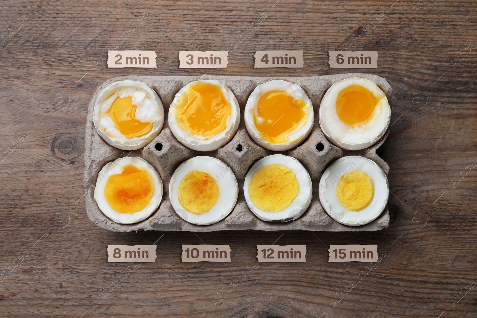 Image of Boiled chicken eggs of different readiness stages in carton on wooden table, top view