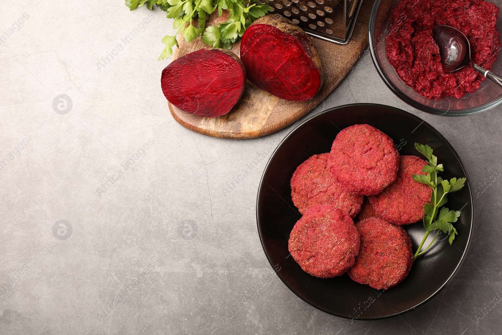 Photo of Delicious beetroot vegan cutlets and ingredients on light gray table, flat lay. Space for text